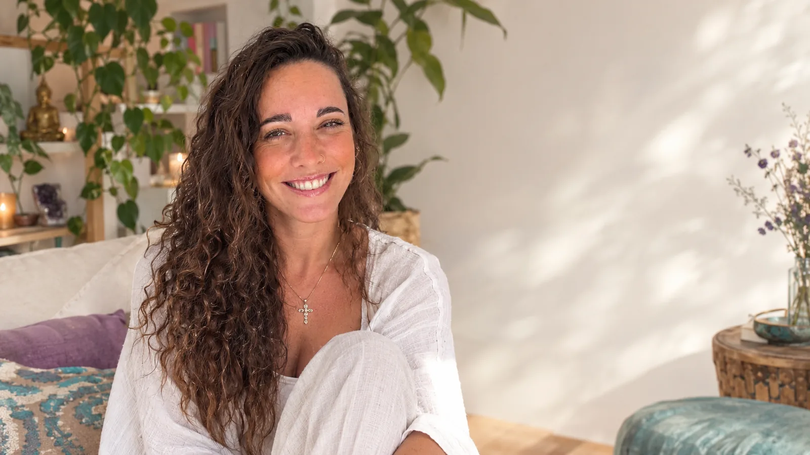 Judith sonriendo en su sofá, con cojines turquesa